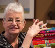 Jacqueline Wilson resting her hands on a pile of her books.