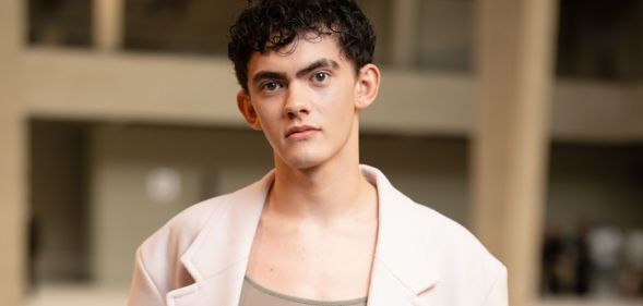 Joe Locke in a brown top and beige blazer, looking directly at the camera.