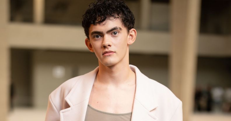 Joe Locke in a brown top and beige blazer, looking directly at the camera.