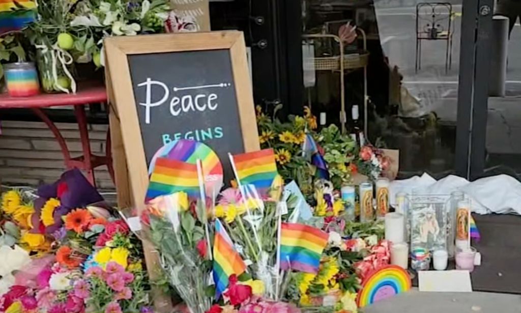 LGBTQ+ Pride flags, flowers and candles are placed outside a California store after its owner, Laura Ann Carleton, was fatally shot in a dispute over a rainbow flag