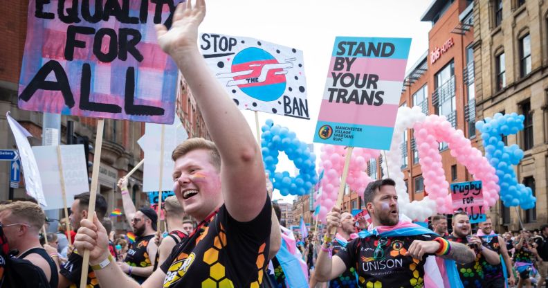 Pro-trans activists march side by side holding up signs of solidarity.
