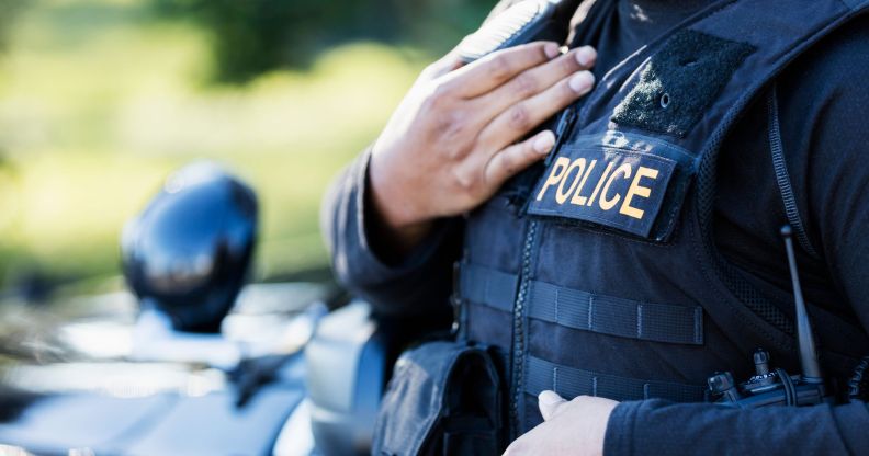 A police officer wearing a vest stood by a police car.