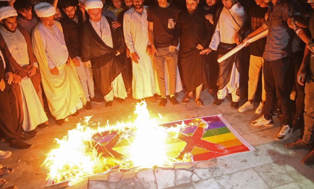 Homophobic protestors in Iraq burn two Pride flags with X's drawn on them