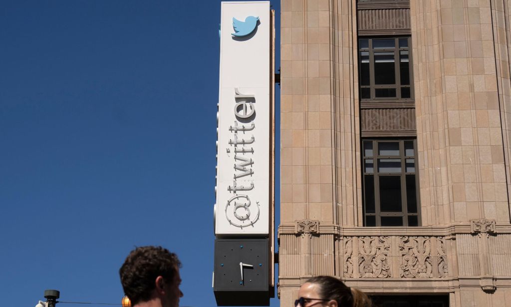 A picture of the half-torn down Twitter HQ sign running along the side of a building.