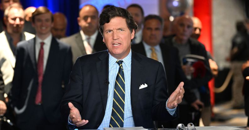 American political commentator Tucker Carlson delivers a talk wearing a suit and tie