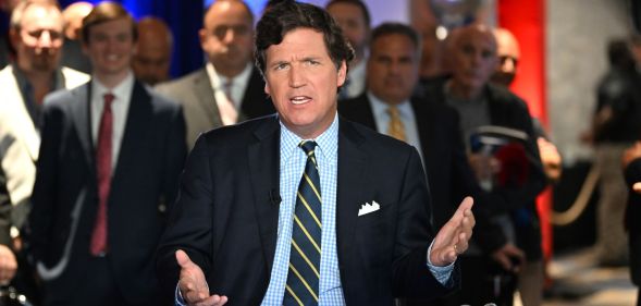 American political commentator Tucker Carlson delivers a talk wearing a suit and tie