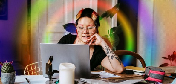 This is an image of a woman working from her home. Her computer is on a table filled with clutter. This imaged is stylised with a rainbow prism effect.
