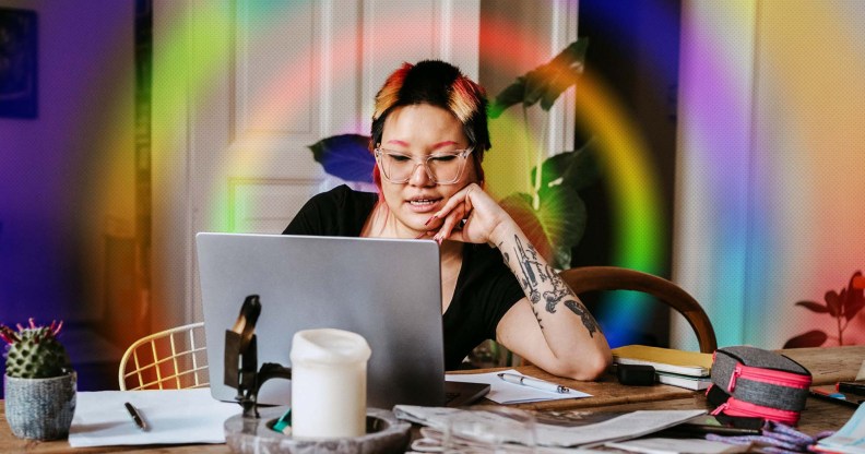 This is an image of a woman working from her home. Her computer is on a table filled with clutter. This imaged is stylised with a rainbow prism effect.