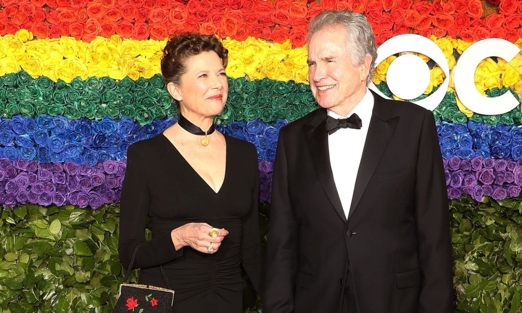 Actress Annette Bening with her husband Warren Beatty stood against a rainbow flower background.