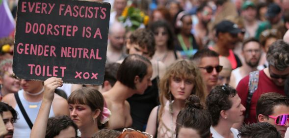 A person holds up a sign reading 'every facist's doorstep is a gender-neutral toilet xxx' during a trans pride protest against anti-trans policies including bathroom bans, restrictions on gender-affirming healthcare and more