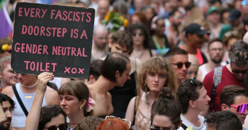 A person holds up a sign reading 'every facist's doorstep is a gender-neutral toilet xxx' during a trans pride protest against anti-trans policies including bathroom bans, restrictions on gender-affirming healthcare and more