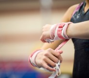 Female gymnast wrapping wrists in preparation, cropped