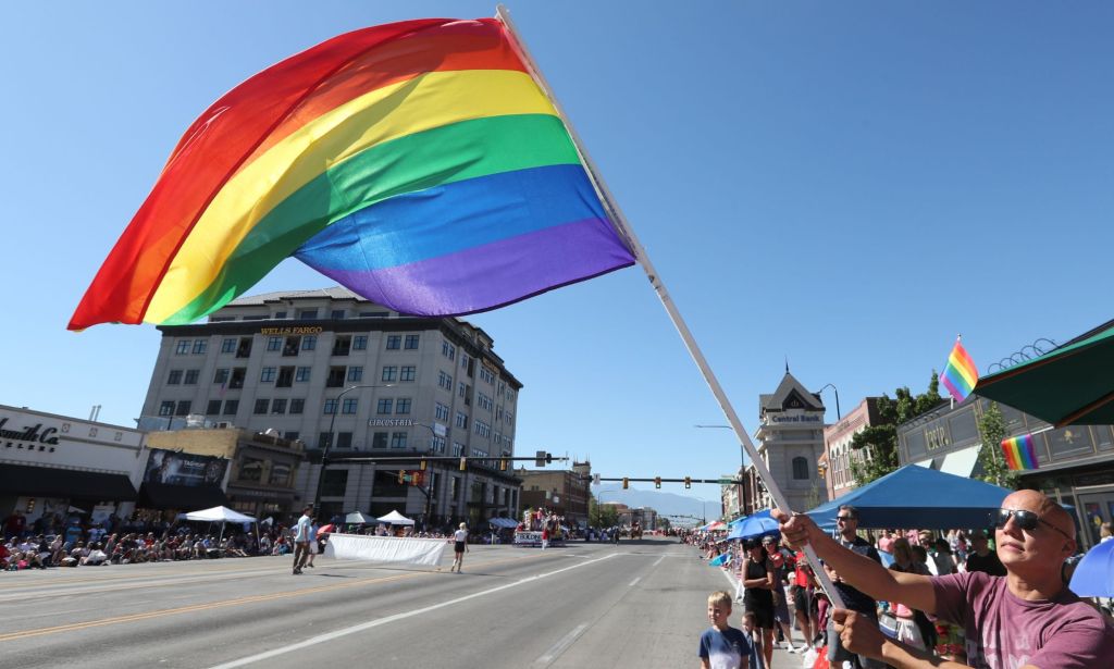 A person waves a rainbow Pride flag in support of the LGBTQ+ and trans community during a protest in Provo, Utah
