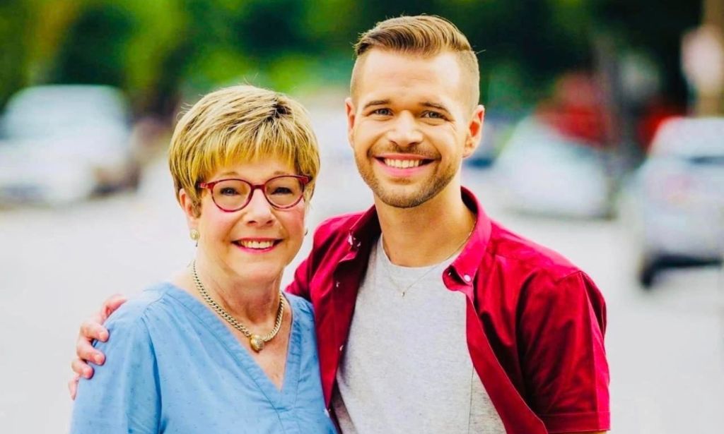 Mama Bears, a support network for moms of LGBTQ+ youth, founder Liz Dyer wears a blue shirt as she stands next to her son who is wearing a white t-shirt with a red shirt on top 