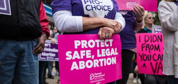 An activist seen holding a placard that says protect safe, legal abortion