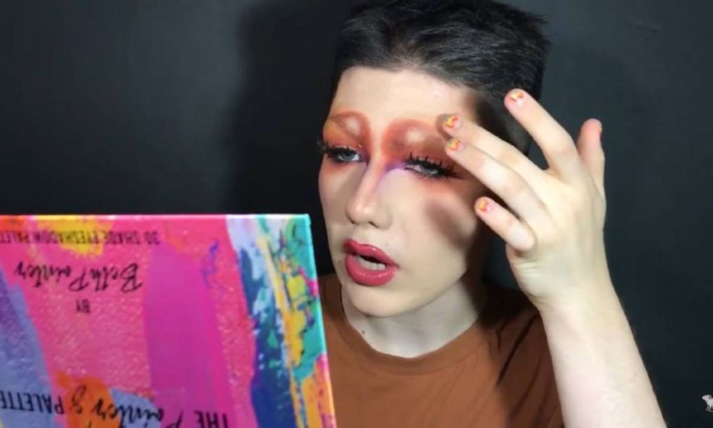 gay Russian university student, Max, holds a makeup palette as she does a beauty tutorial