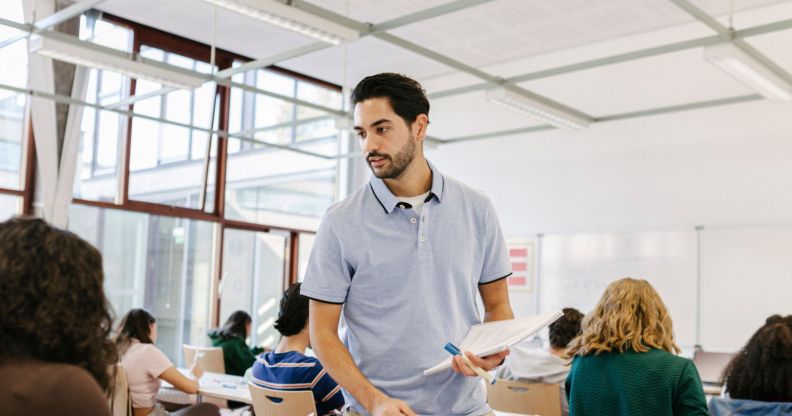 Photo of a teacher standing in a classroom surrounded by secondary age students