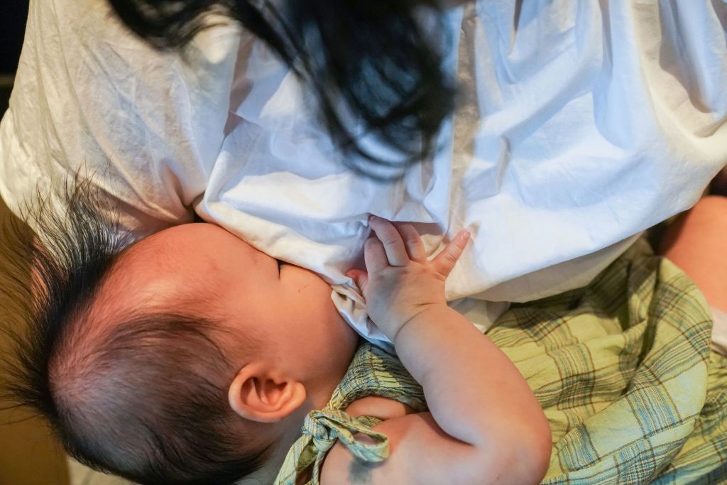 A woman breastfeeds her child in Shanghai. The picture shows a baby drinking milk from their mother's breast as she looks down at the child.