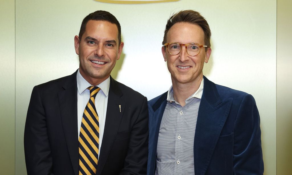 Openly gay Australian MP Alex Greenwich, who has received homophobic hate online, wears a suit and tie as he stands next to his husband Victor Hoeld