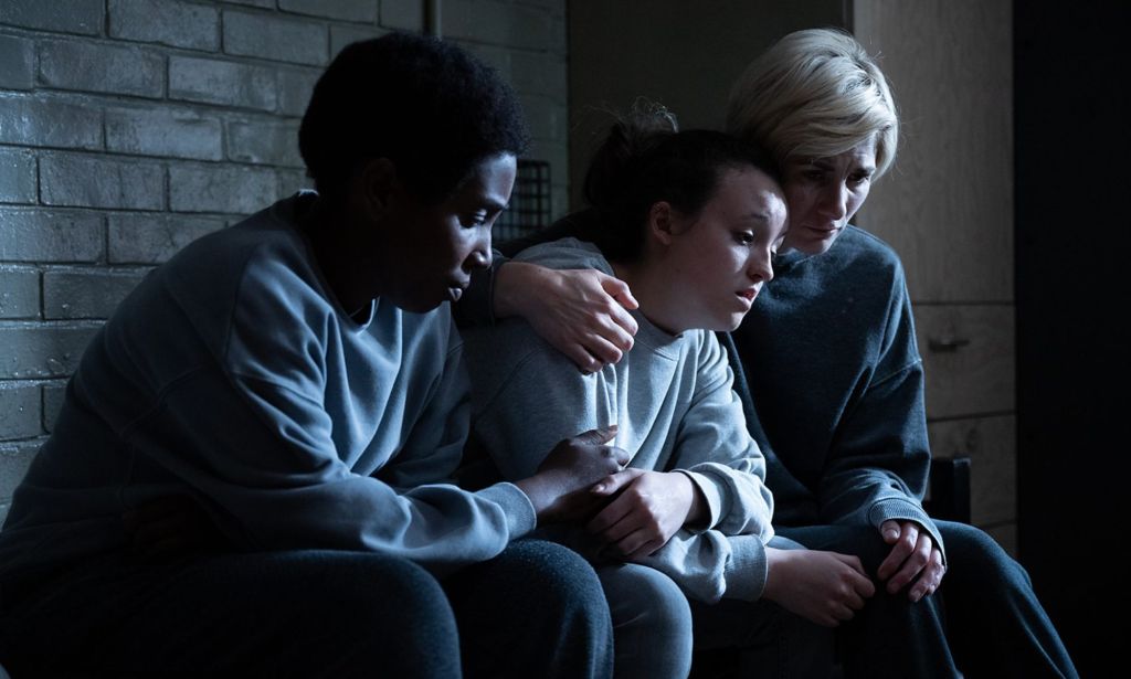 Bella Ramsey's Kelsey is comforted by fellow inmates Orla (Jodie Whittaker) and Abi (Tamara Lawrance). (BBC)
