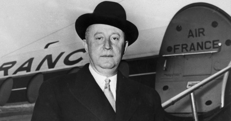 A black and white photo of fashion designer Christian Dior stood in front of an Air France plane.