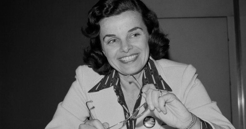 A black and white picture of Dianne Feinstein smiling as she holds a pair of glasses.