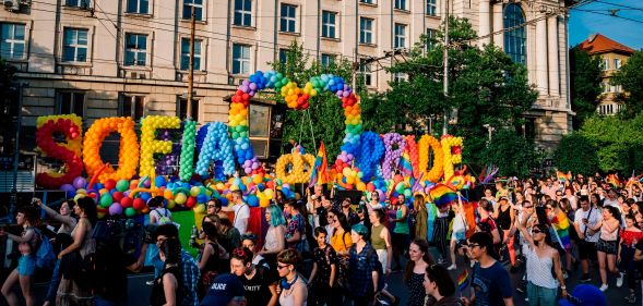 Revellers take part in a Pride parade in Sofia, Bulgaria in 2019 - a large sign written in balloons reads "Sofia Pride"