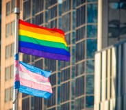Rainbow flag and Trans flag on a flagpole in front of office buildings