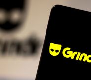 This is an image of a mobile phone with the Grindr logo in bright yellow.