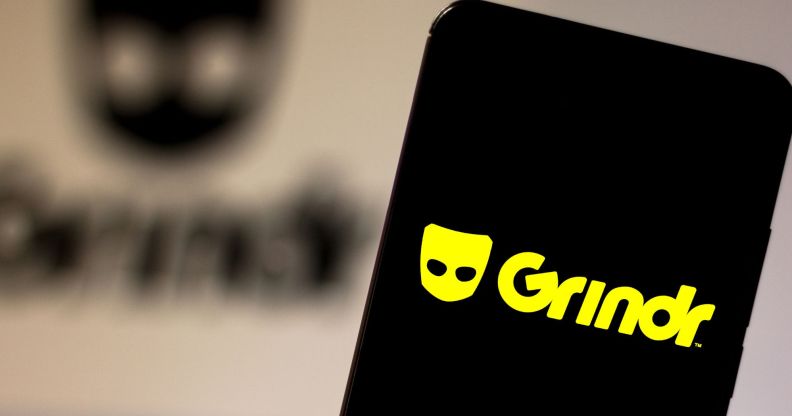 This is an image of a mobile phone with the Grindr logo in bright yellow.