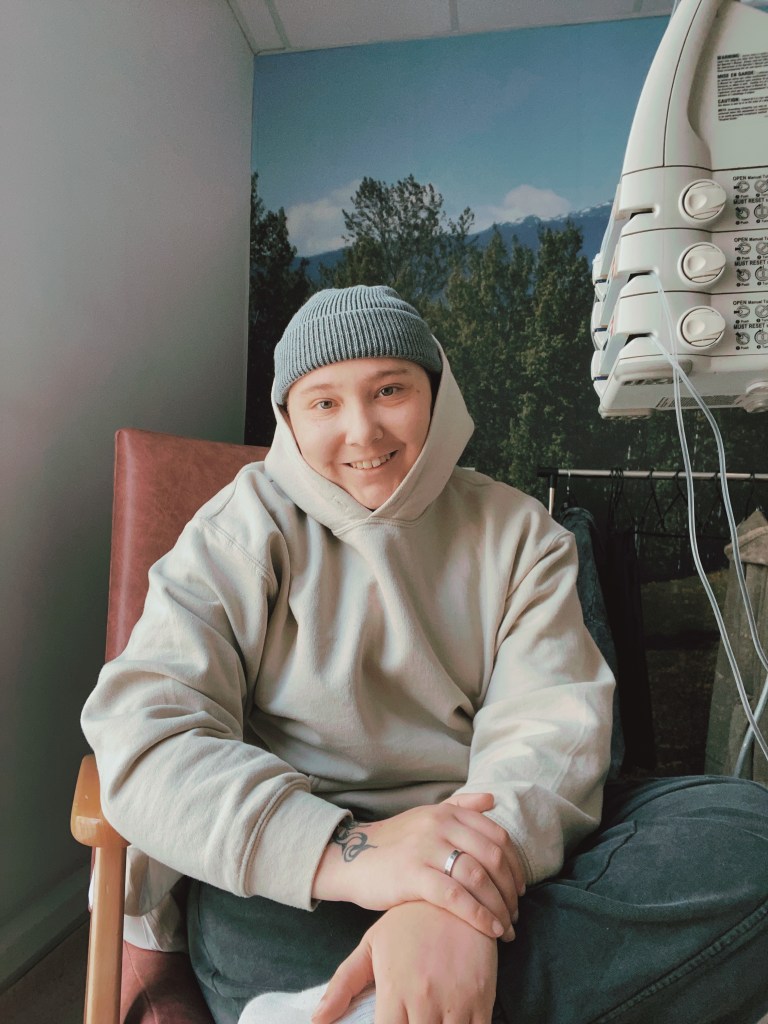 Hex Coles during treatment. They are pictured wearing a hoodie and a hat in a hospital chair.
LGBTQ+ survivors share their experiences of navigating the world of online dating after cancer or another serious illness.