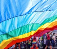 An LGBTQ+ flag draped over protestors.