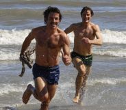 Jonathan Bailey and Matt Bailey chase each other on a beach in a still from Fellow Travelers.