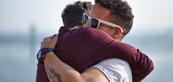 Two middle-aged men hug each other.