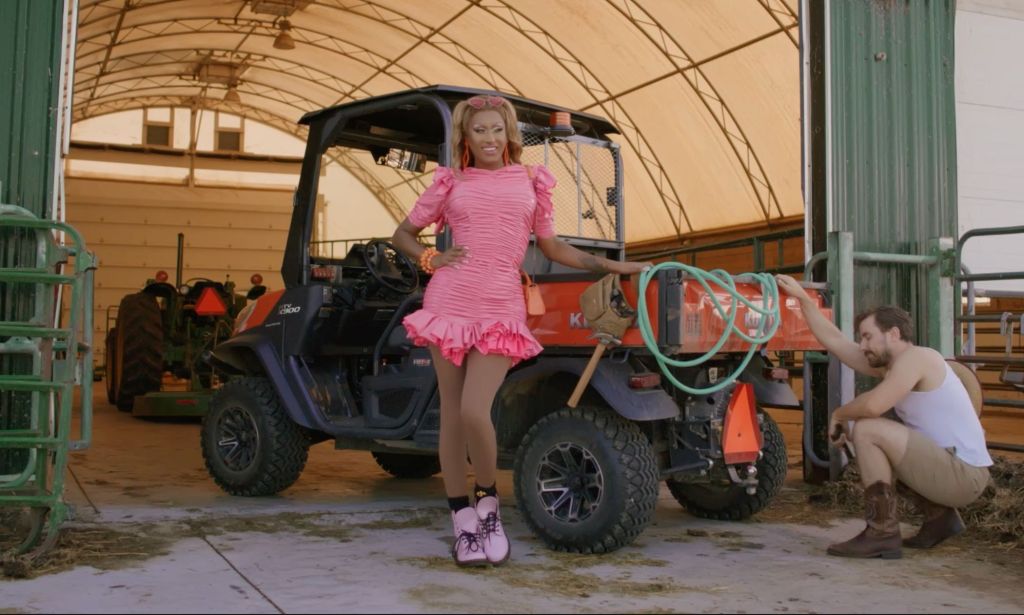 A still from Priyanka's upcoming film It's All Sunshine and Rainbows. Priyanka, as Melonie Sunshine, is stood by a tractor while Nick Rainbow crouches by a tractor.