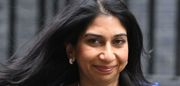 Suella Braverman, smiling as she walks down a walkway.