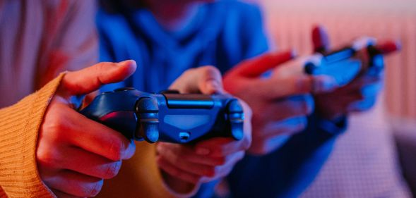 Two people play video games using game controllers.