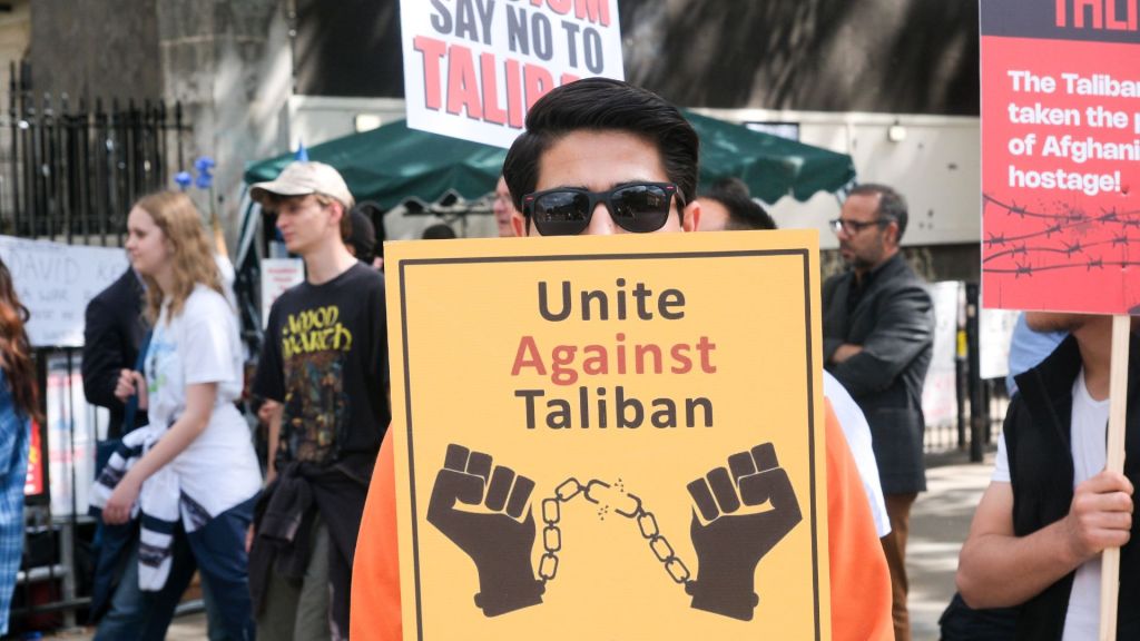 Protester holds up a sign reading "unite against Taliban"