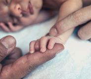 Stock image of newborn baby's hand holding the finger of their parent