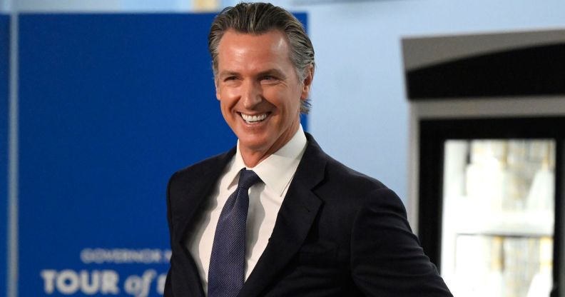 California governor Gavin Newsom, who supported an anti-book ban bill, smiles as he wears a white shirt, blue tie and dark suit jacket