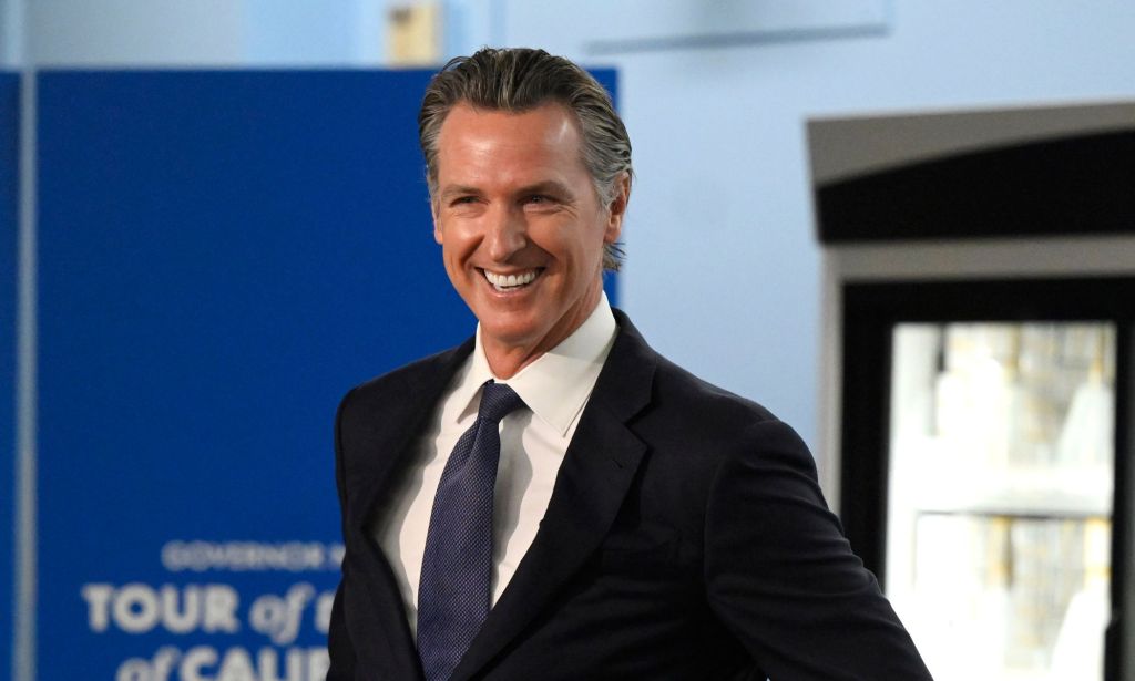 California governor Gavin Newsom, who supported an anti-book ban bill, smiles as he wears a white shirt, blue tie and dark suit jacket
