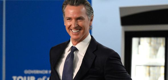 California governor Gavin Newsom, who supported an anti-book ban bill, smiles as he wears a white shirt, blue tie and dark suit jacket