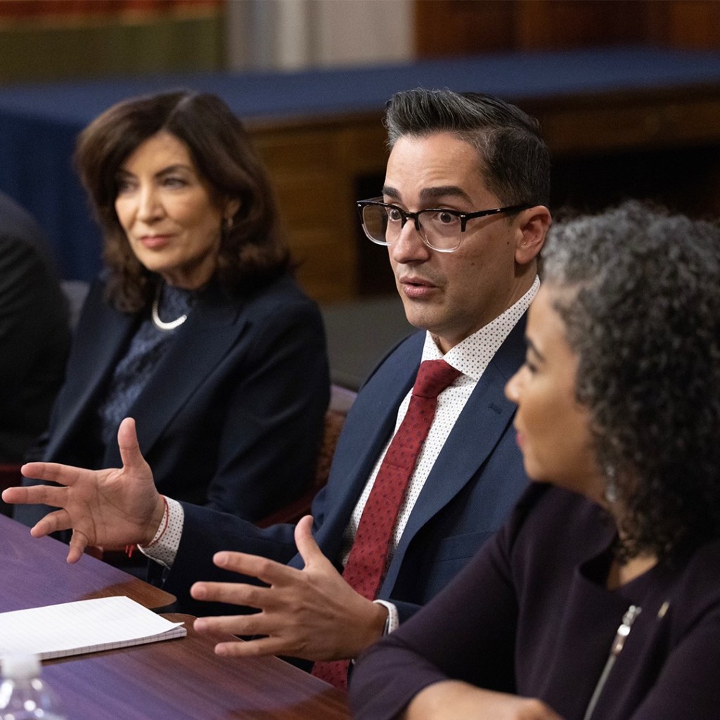 Frankie Miranda, the first openly LGBTQ+ president of the Hispanic Federation, wears a suit and tie as he talks to others at the New York Governor's Office