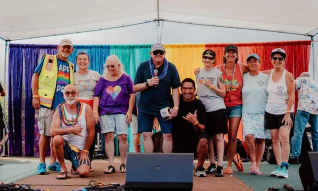 Members of Aloha Maui Pride, a local LGBTQ+ nonprofit in Hawaii, pose together on stage during a Pride event. The group has put together a fundraiser to support queer folks and businesses impacted the by Maui wildfires