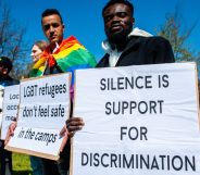 People hold up signs bringing awareness to the plight of LGBTQ+ people seeking asylum abroad including a sign reading 'silence is support for discrimination' and another reading 'LGBT refugees don't feel safe in the camps'
