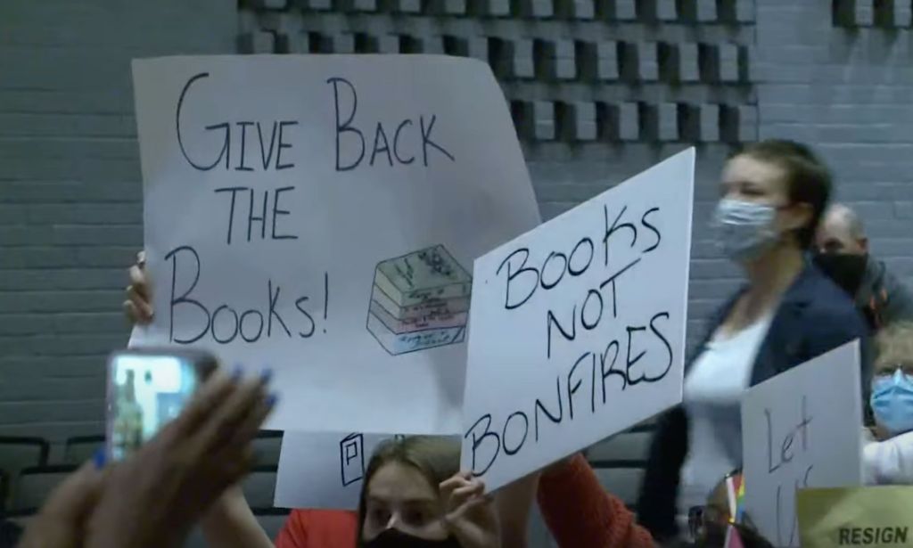 Two people hold up signs reading 'Give back the books' and 'Books not bonfires' after two Spotsylvania County Public Schools advocated for banning and burning LGBTQ-inclusive books