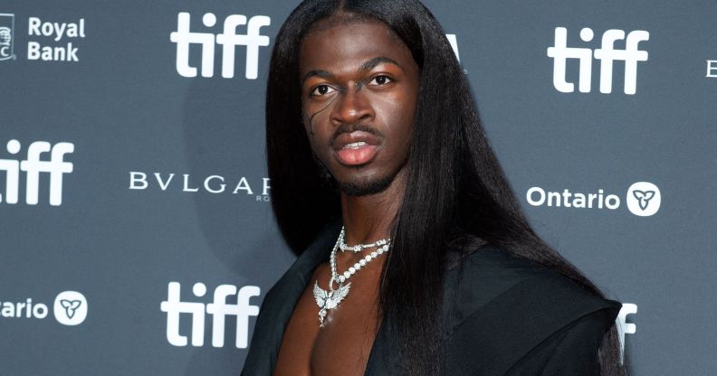 Lil Nas X wears long black hair and a black jacket at the premiere of his documentary, which was delayed because of a bomb threat