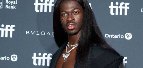 Lil Nas X wears long black hair and a black jacket at the premiere of his documentary, which was delayed because of a bomb threat