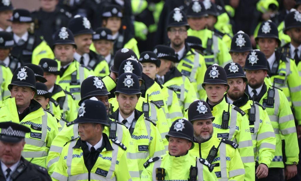 Several Metropolitan Police officers, wearing yellow reflective gear, walk together in a crowd.  The force has been accused of fostering a homophobic and sexist environment in the past