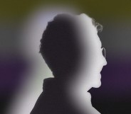The image shows a silhouette of a person standing in side-profile against the non-binary flag colours.